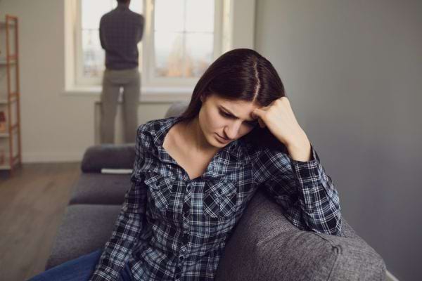 Une femme pensive et inquiète assise sur un canapé.