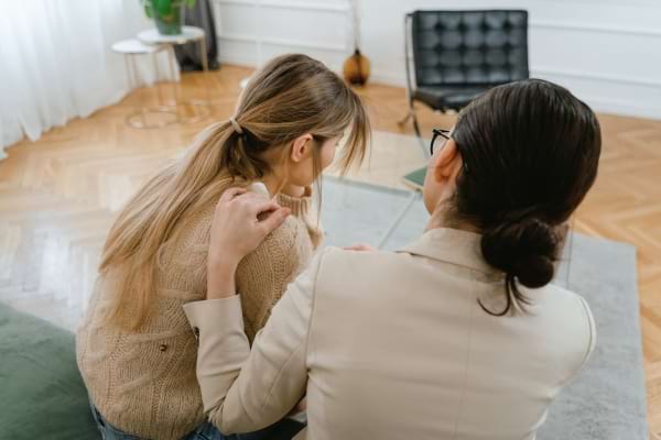 Une femme pose sa main sur l’épaule d’une autre pour la réconforter.