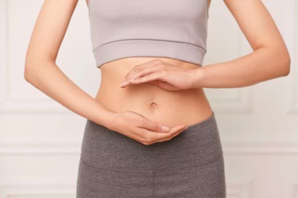 Femme posant ses mains autour de son ventre en signe de bien-être.