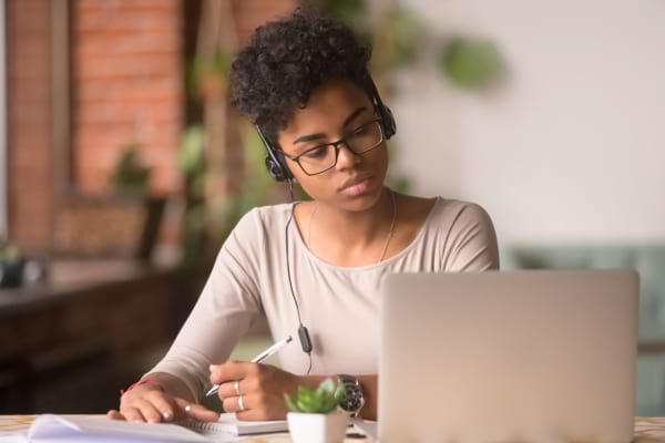 Une jeune femme portant un casque audio travaille concentrée devant un ordinateur portable.