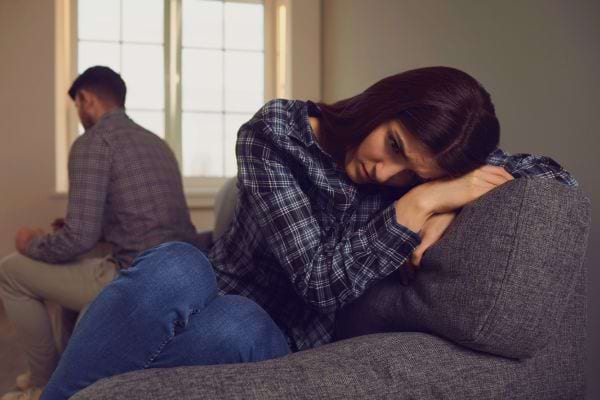 Une femme triste assise sur un canapé après une dispute.