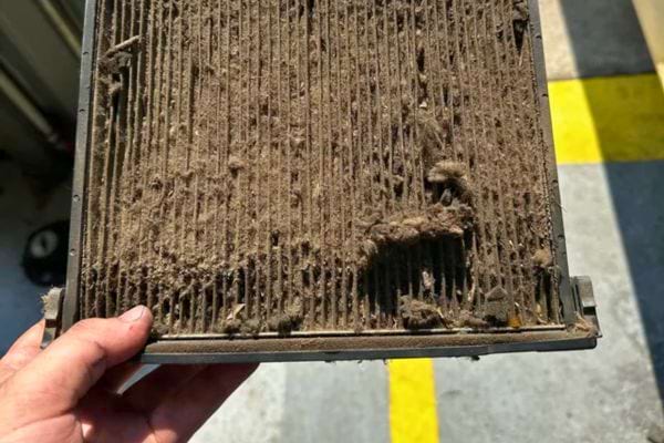 Un filtre à air très sale couvert de poussière et de débris.