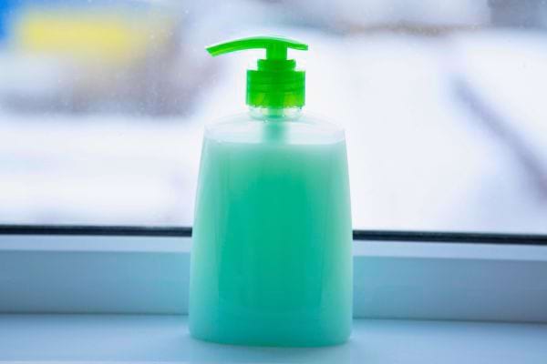Un flacon pompe vert est rempli de savon ou lotion liquide.