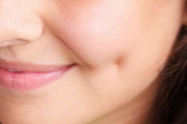 Une femme affiche un léger sourire avec des fossettes marquées.