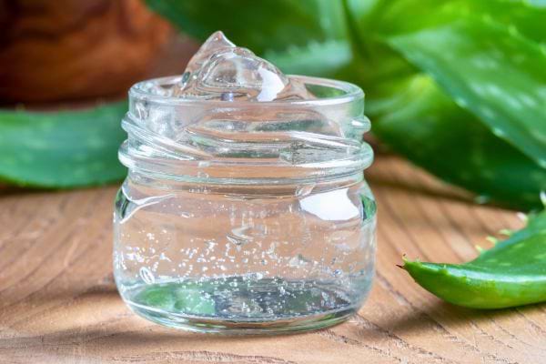 Un petit pot en verre contient du gel d’aloe vera transparent.