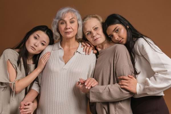 Quatre femmes de générations différentes posent ensemble et se soutiennent.