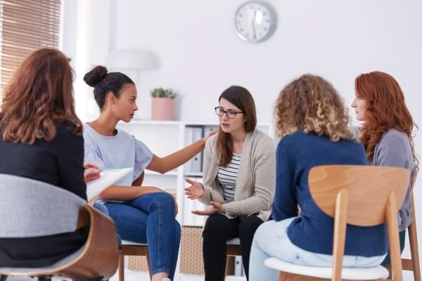 Un groupe de femmes discute, l’une est réconfortée par une autre.