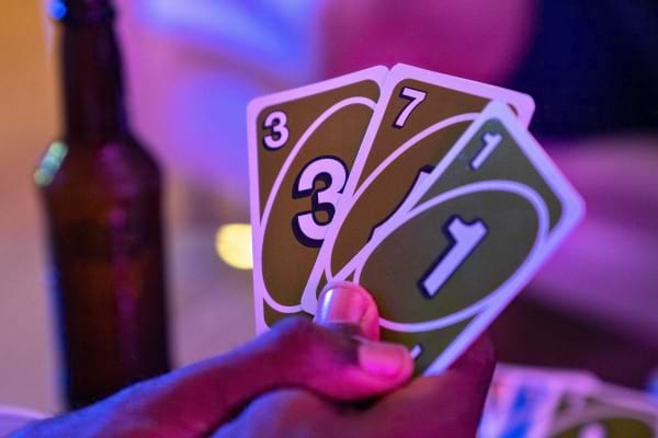 Un joueur tient trois cartes Uno vertes numerotees dans une ambiance lumineuse.