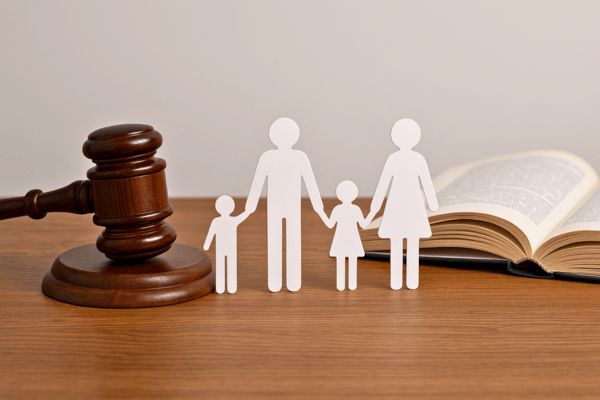 Un livre de droit et un maillet sont posés à côté de figurines représentant une famille.