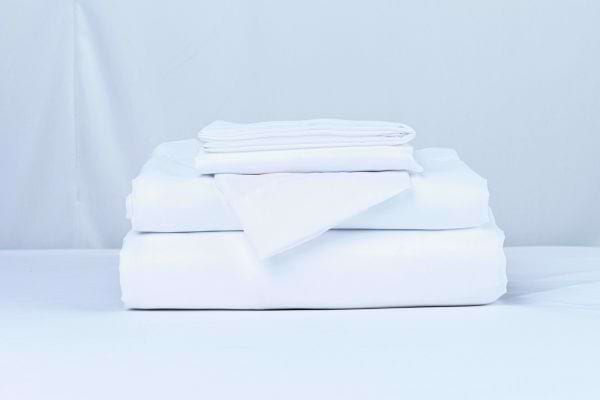 Des draps et taies blancs parfaitement pliés posés les uns sur les autres.