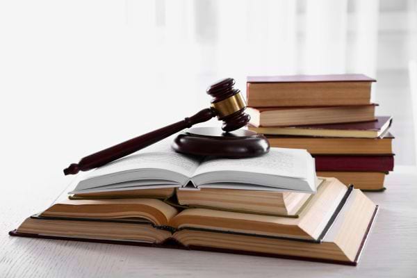 Un marteau de juge posé sur des livres de droit ouverts et empilés.