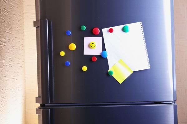 Un réfrigérateur gris avec des magnets colorés et des notes collées.