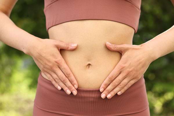 Une femme pose ses mains sur son ventre, illustrant l’attention portée à la digestion.