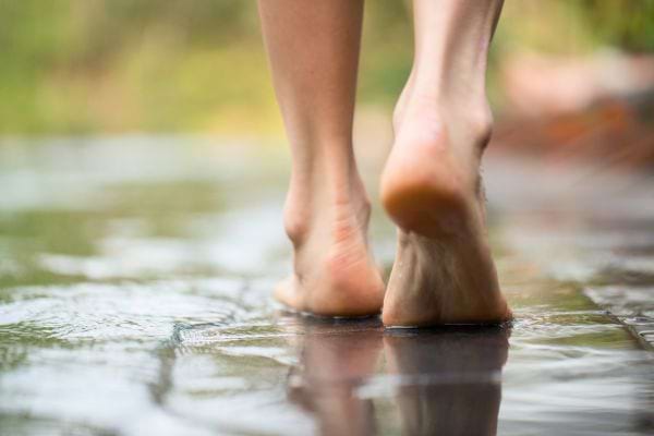 Une personne marche pieds nus sur un sol mouillé.