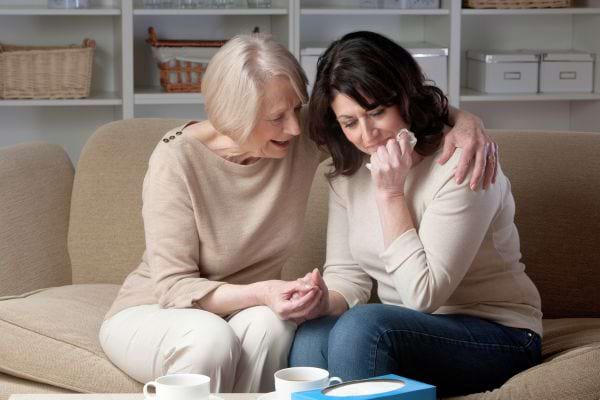 Une mère entoure sa fille en pleurs pour lui apporter du réconfort.