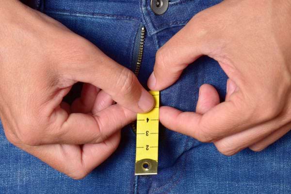 Un ruban de mesure utilisé sur un jean fermé.
