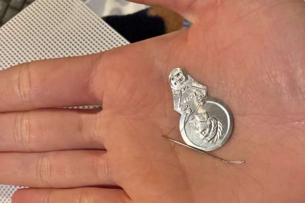 Un petit passe-fil ancien posé dans la paume d’une main.