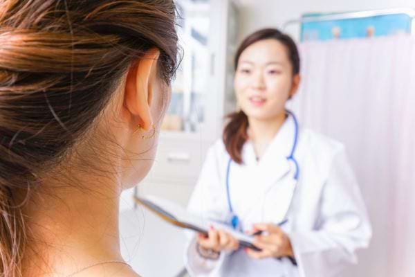 Une patiente discute avec une médecin en blouse blanche tenant un dossier médical.