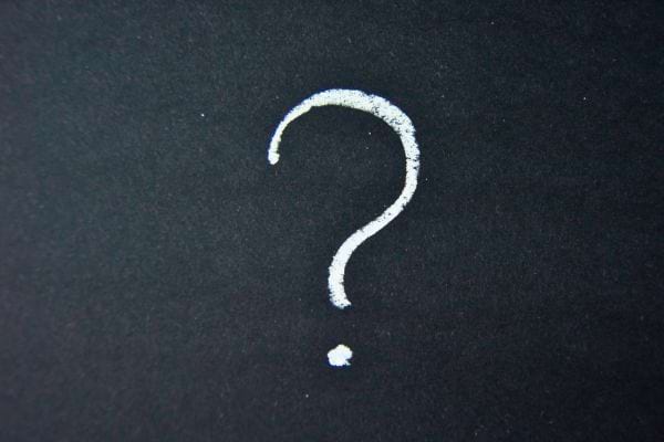 Un point d’interrogation dessiné à la craie blanche sur fond noir.