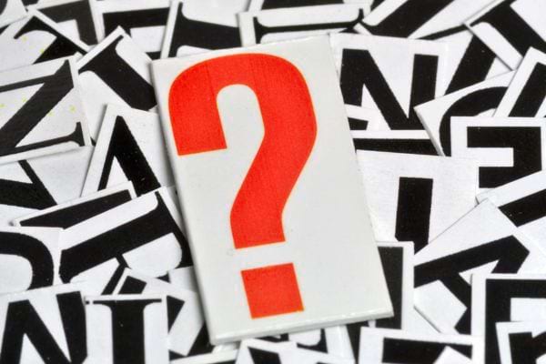 Un grand point d’interrogation rouge ressort sur un fond de lettres.