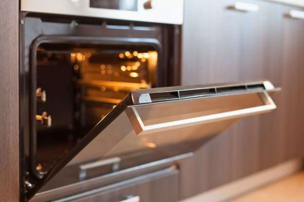 Porte d’un four entrouverte dans une cuisine.