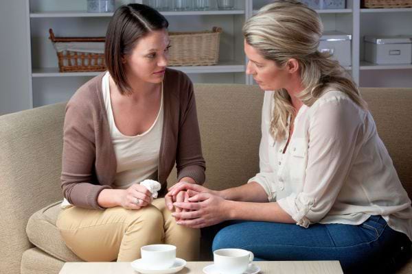 Deux femmes discutent, l’une console l’autre.