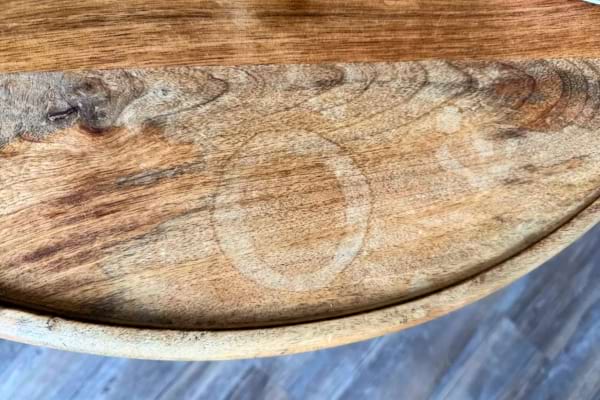 Une table en bois montre une marque ronde d’humidité incrustée.