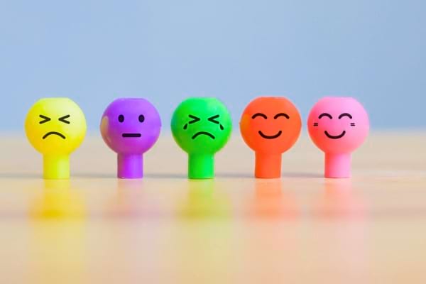 Cinq figurines colorées alignées affichent différentes émotions avec des visages dessinés.