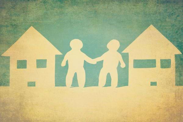 Illustration de deux personnages en papier se tenant la main entre deux maisons.