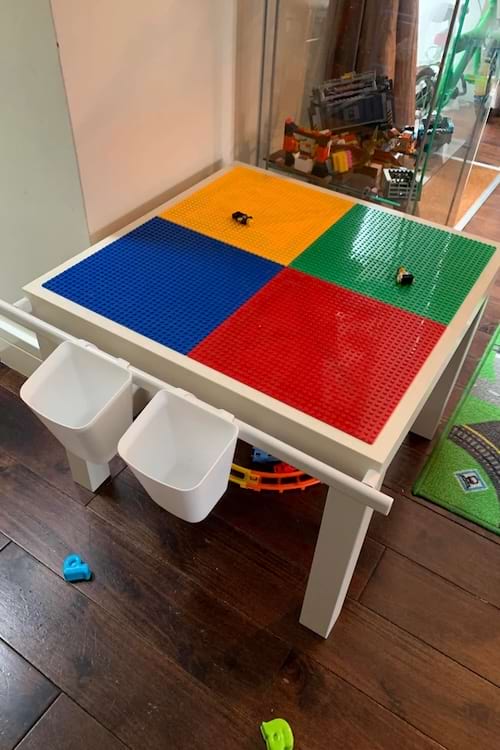 Table pour enfants transformée en surface de jeu Lego avec godets suspendus pour le rangement des pièces.