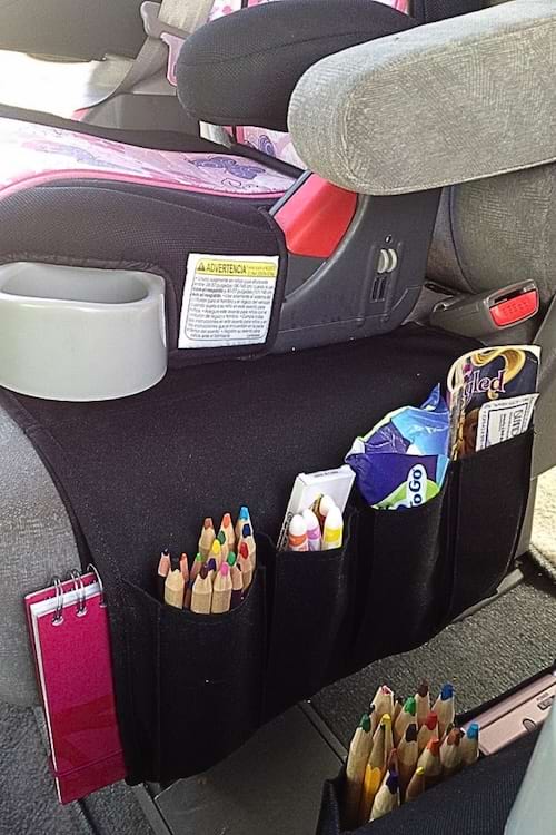 Organisateur suspendu au siège de voiture contenant crayons, cahiers et collations pour enfant.
