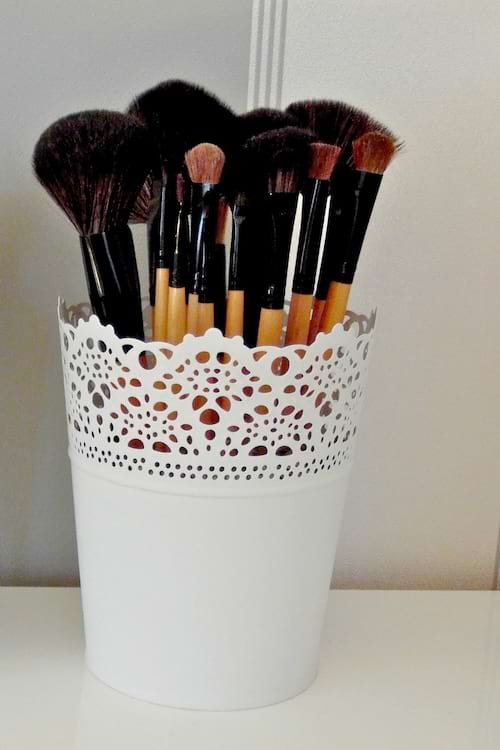 Des pots décoratifs ajourés sont utilisés comme rangement pratique pour des pinceaux de maquillage.