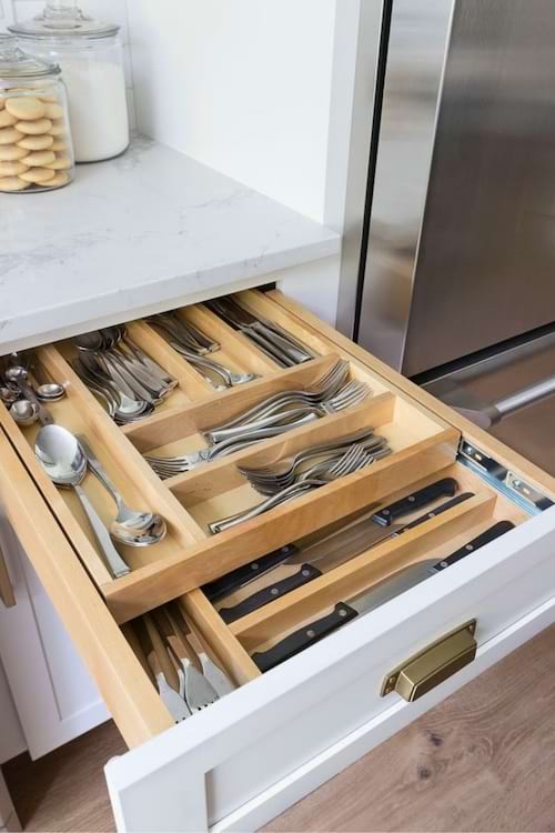 Un tiroir discret est intégré dans la plinthe d’un meuble de cuisine pour optimiser l’espace de rangement.