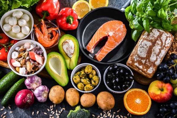 Un assortiment d’aliments sains avec du saumon, légumes et fruits colorés.
