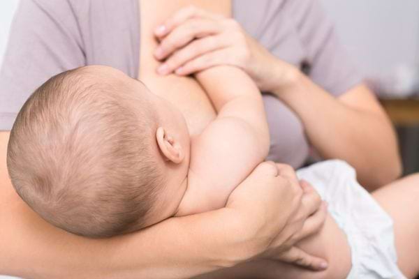 Une mère allaite tendrement son bébé dans ses bras.