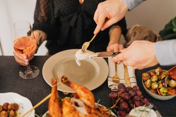 Personne découpe un poulet rôti lors d’un repas convivial.