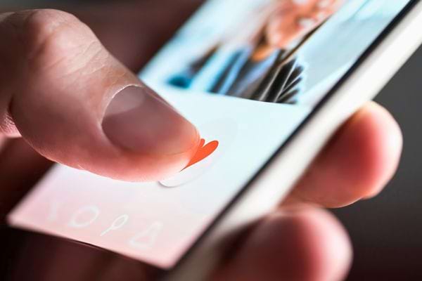 Doigt appuie sur un cœur rouge sur une application de rencontre.
