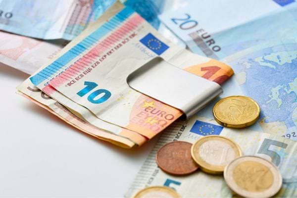 Billets et pièces en euros étalés sur une surface blanche.