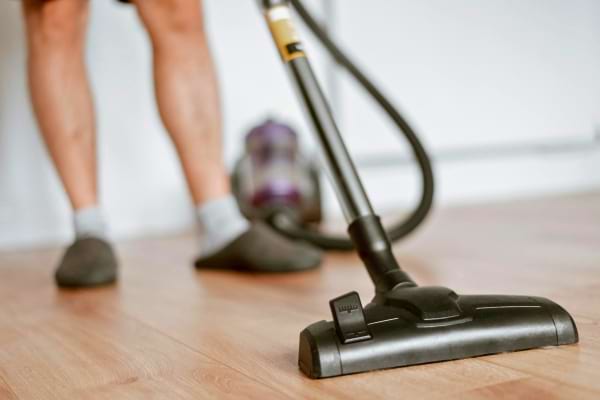 Une personne passe l’aspirateur sur un sol en bois clair.