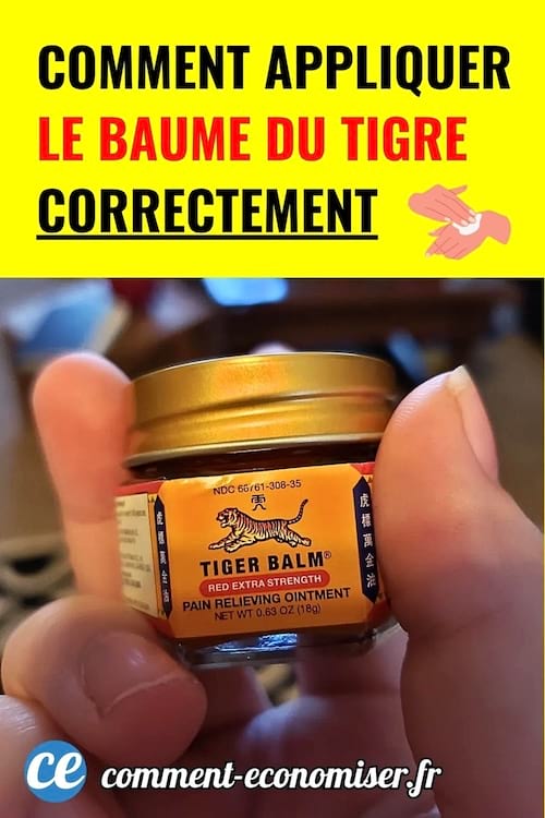 Main tenant un petit pot de baume du tigre rouge.