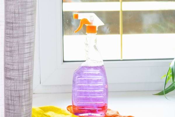 Pulvérisateur transparent contenant un liquide violet posé près d’une fenêtre.