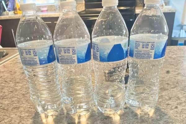 Quatre bouteilles d’eau en plastique posées sur un plan de travail.