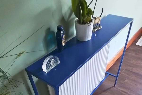 Cache-radiateur bleu transformé en meuble décoratif avec plante et objets.