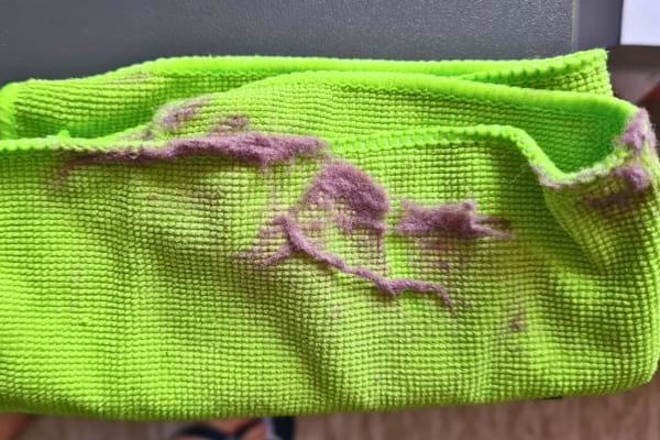 Un chiffon microfibre vert retient de la poussière violette après le nettoyage.