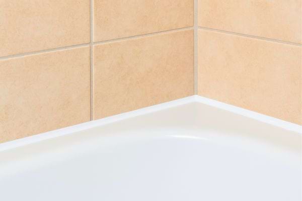 Coin de baignoire propre avec carrelage clair bien aligné.