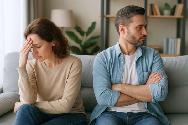 Couple fâché assis sur un canapé, chacun regarde de son côté.