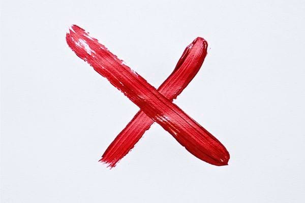 Une croix rouge peinte grossièrement sur un fond blanc.