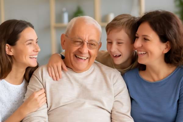 un grand-parent souriant entouré de sa famille, ambiance joyeuse et sereine.