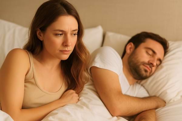 une femme regarde son partenaire endormi après un rapport amoureux