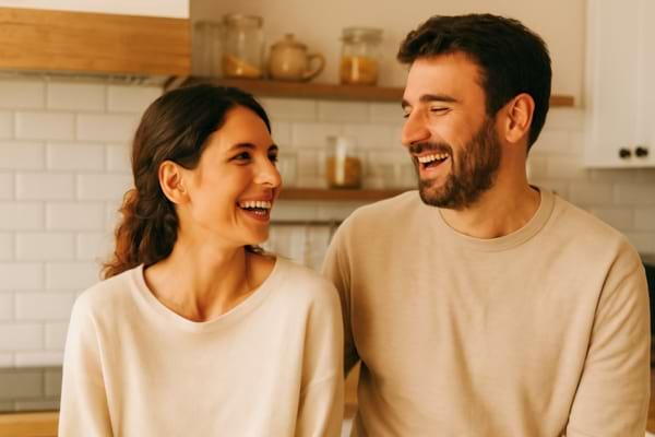 Un couple riant ensemble dans une cuisine, ambiance douce et familière.
